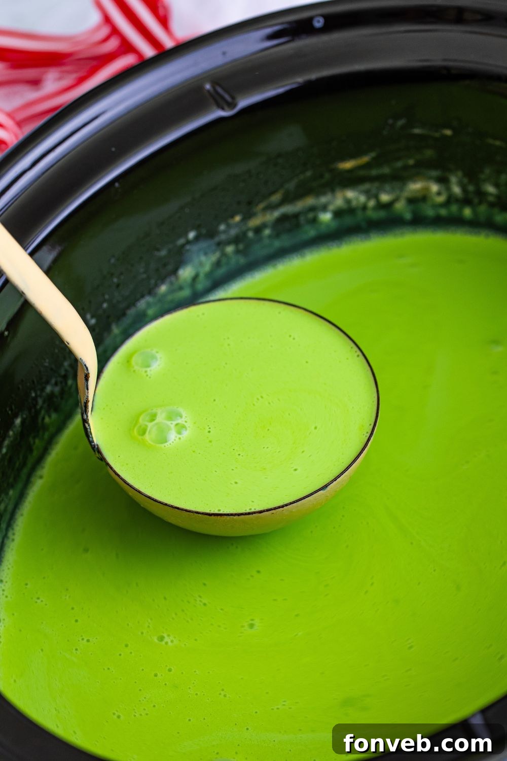 Ladle scooping Grinch Hot Chocolate from a slow cooker