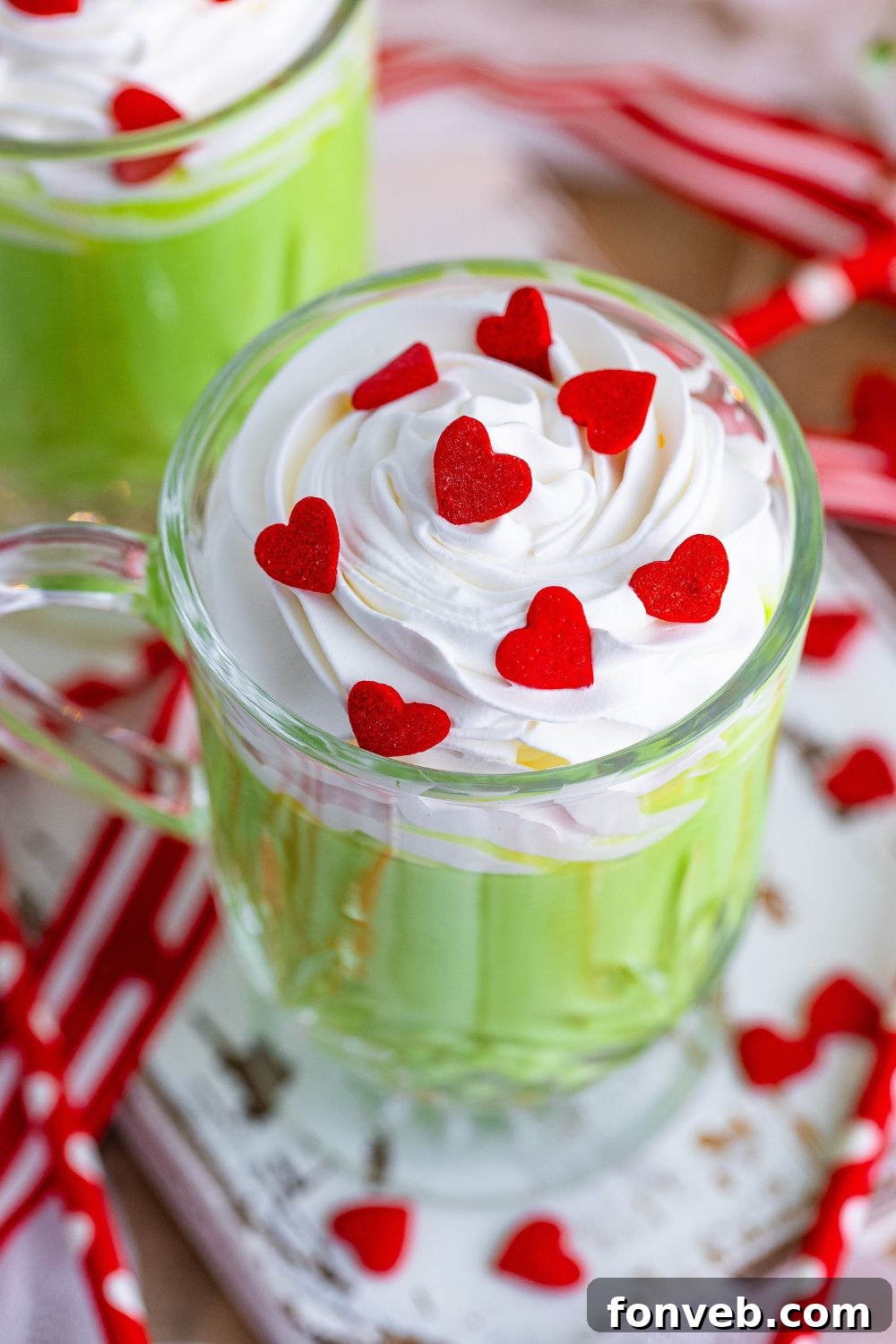 Overhead shot of Grinch hot chocolate in a glass mug with whipped cream and sprinkles