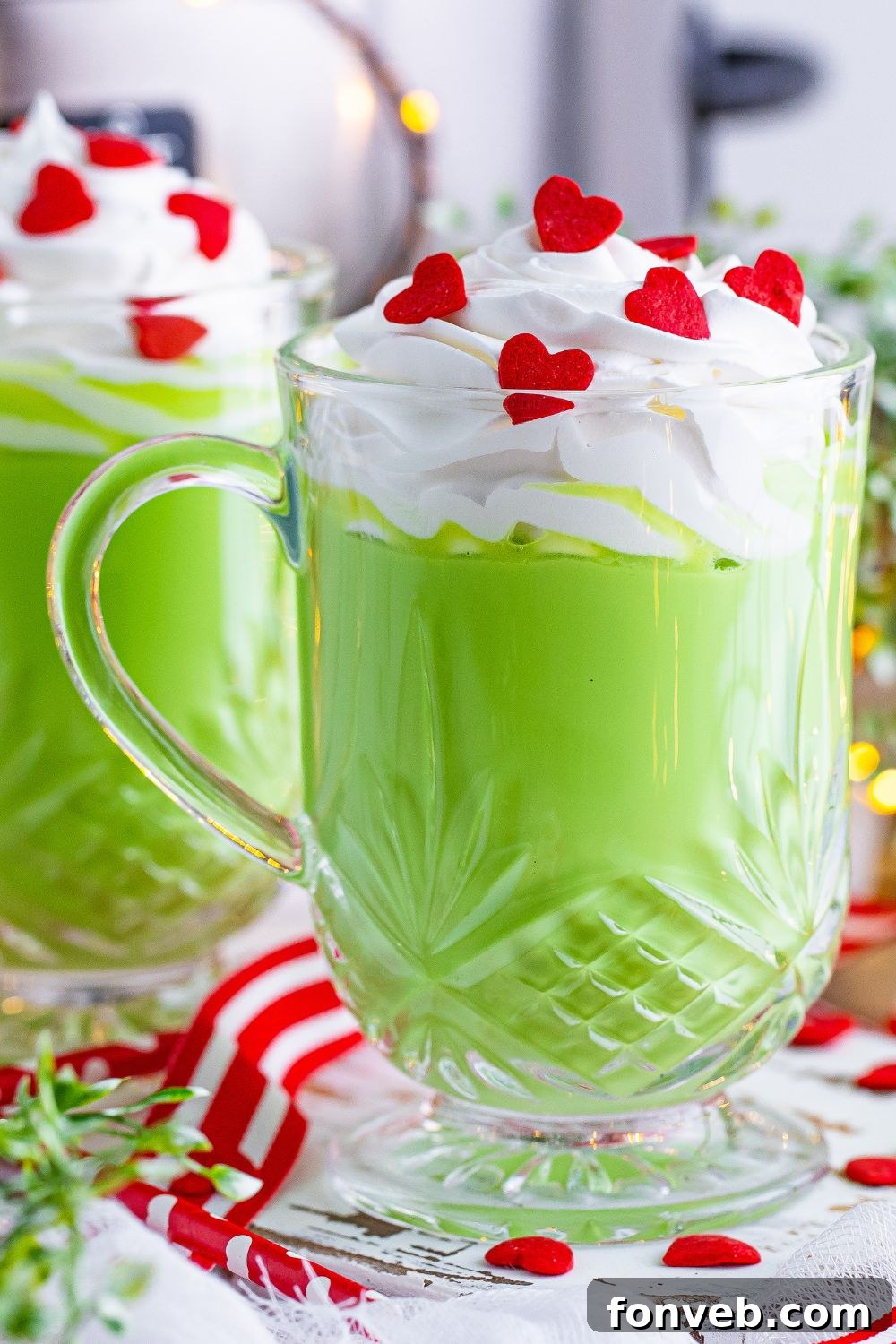 Grinch hot chocolate with whipped cream and sprinkles in a festive mug