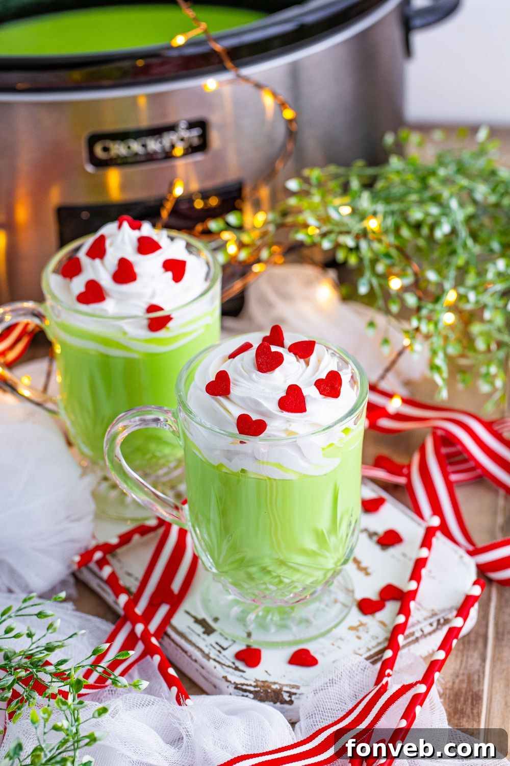 Two glasses of vibrant green Grinch Hot Chocolate on a rustic wooden table