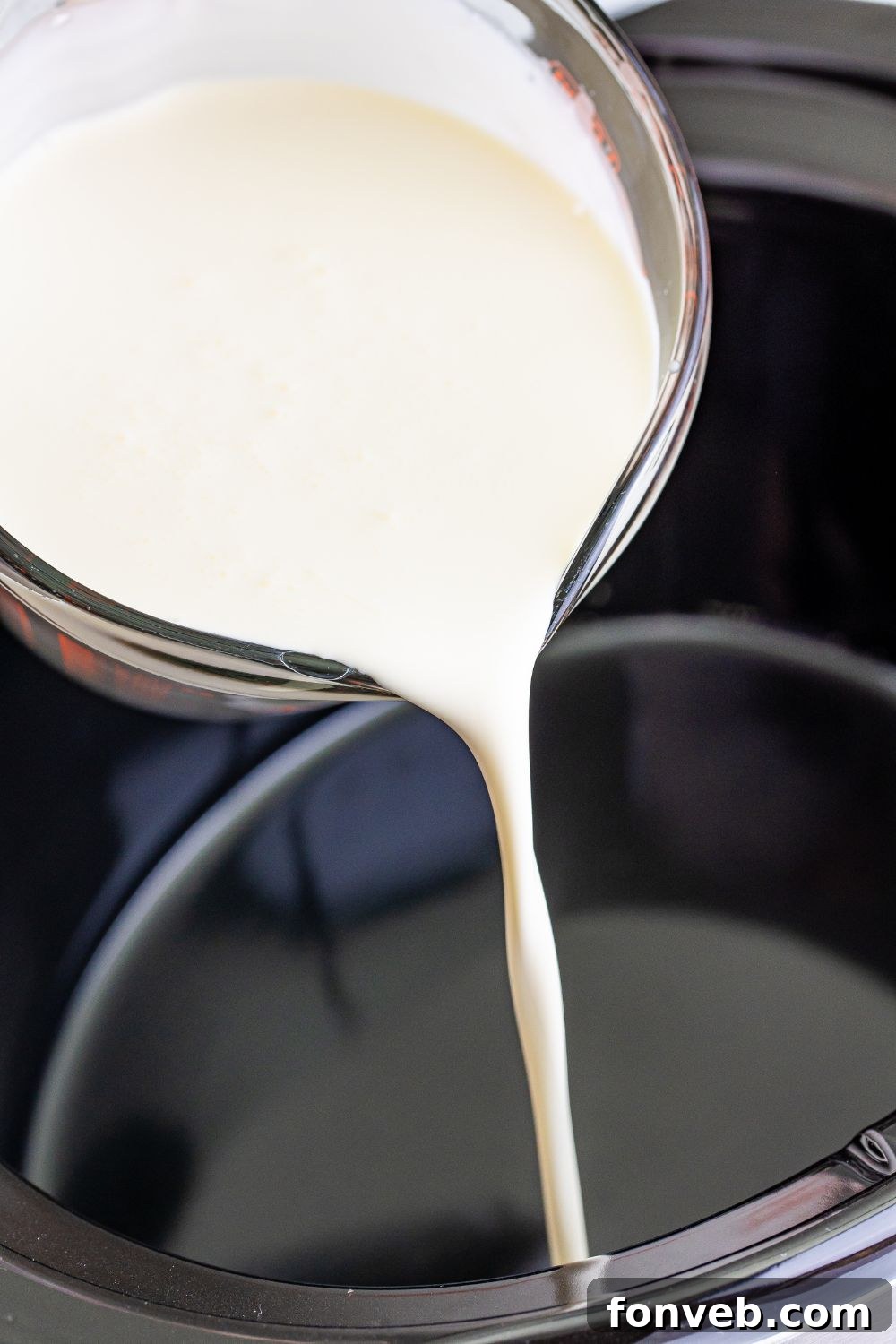 Pouring heavy cream into a slow cooker for hot chocolate