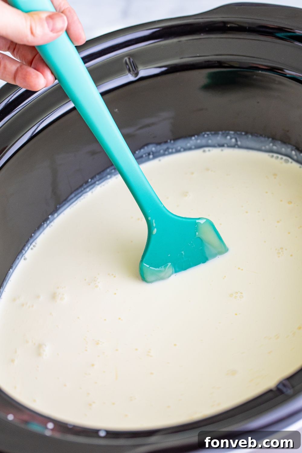 Stirring Grinch hot chocolate ingredients gently in a slow cooker