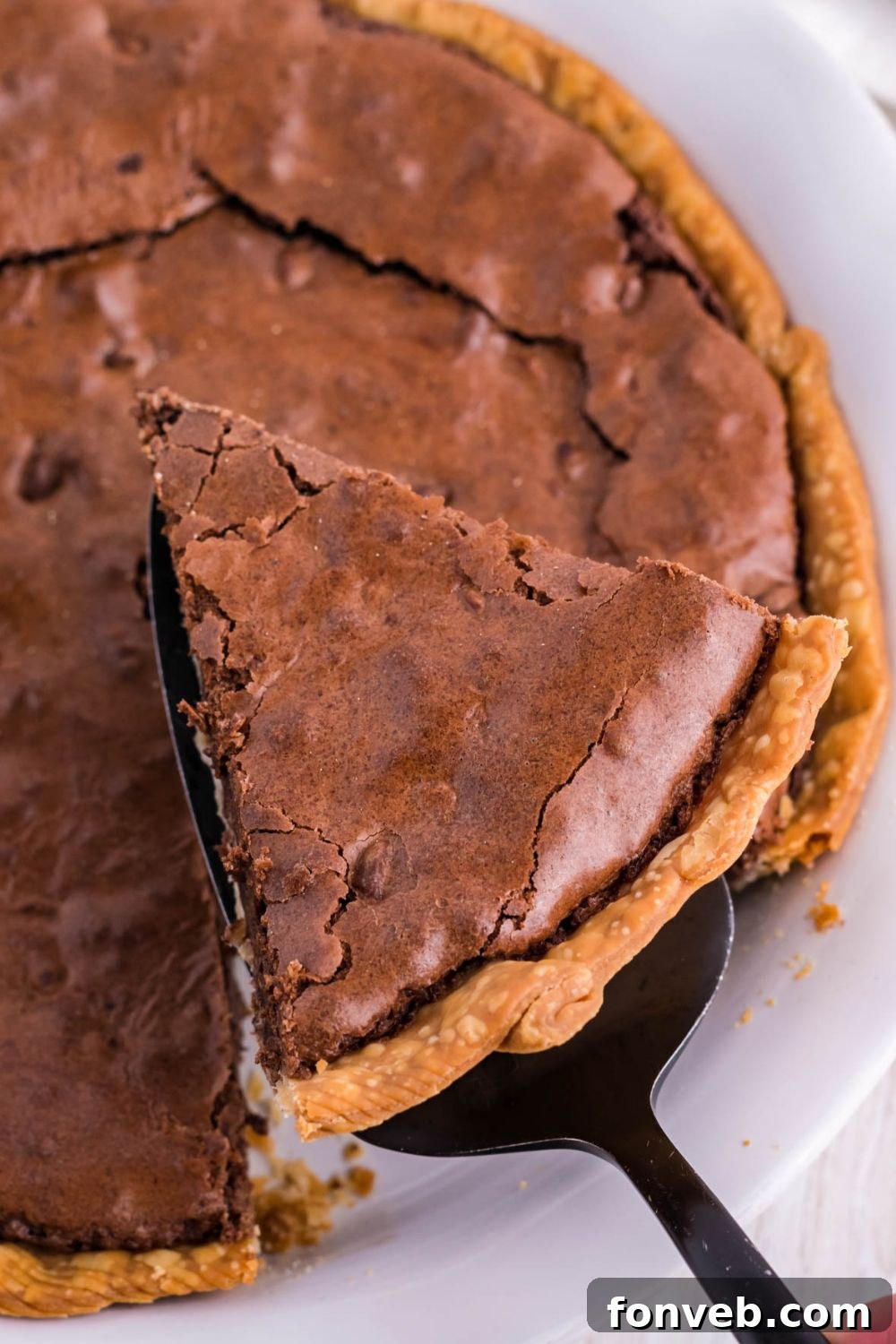 Fudgy Brownie Pie Perfection 11 A large slice of brownie pie being lifted out of the pie pan with a spatula.