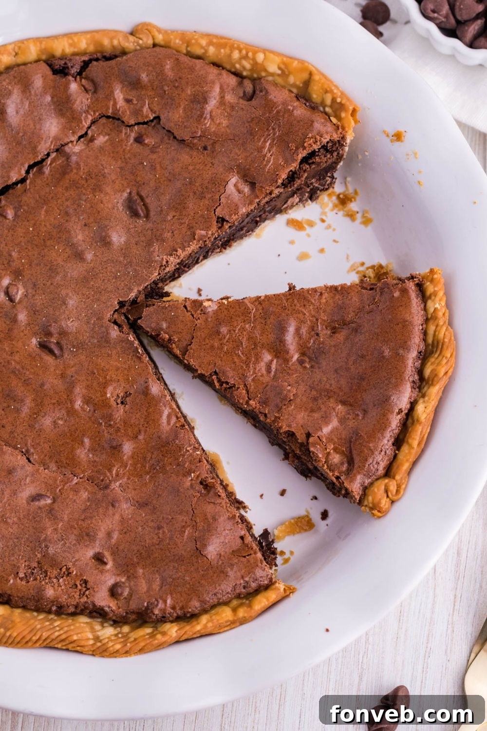 Fudgy Brownie Pie Perfection 14 A baked brownie pie in its pan, with a large slice already taken out.