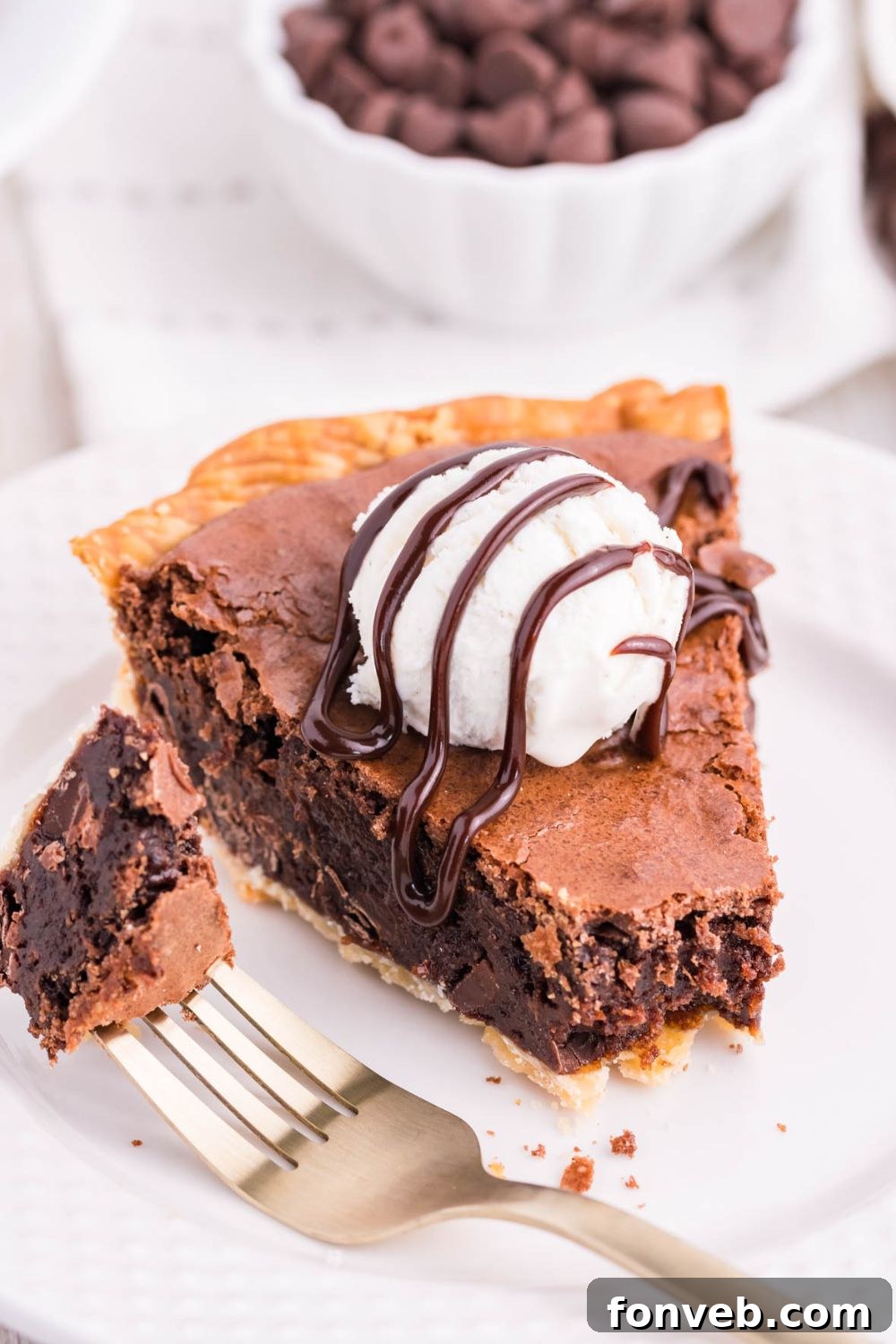 Fudgy Brownie Pie Perfection 16 A fork holding a bite of brownie fudge pie, next to a slice on a plate.
