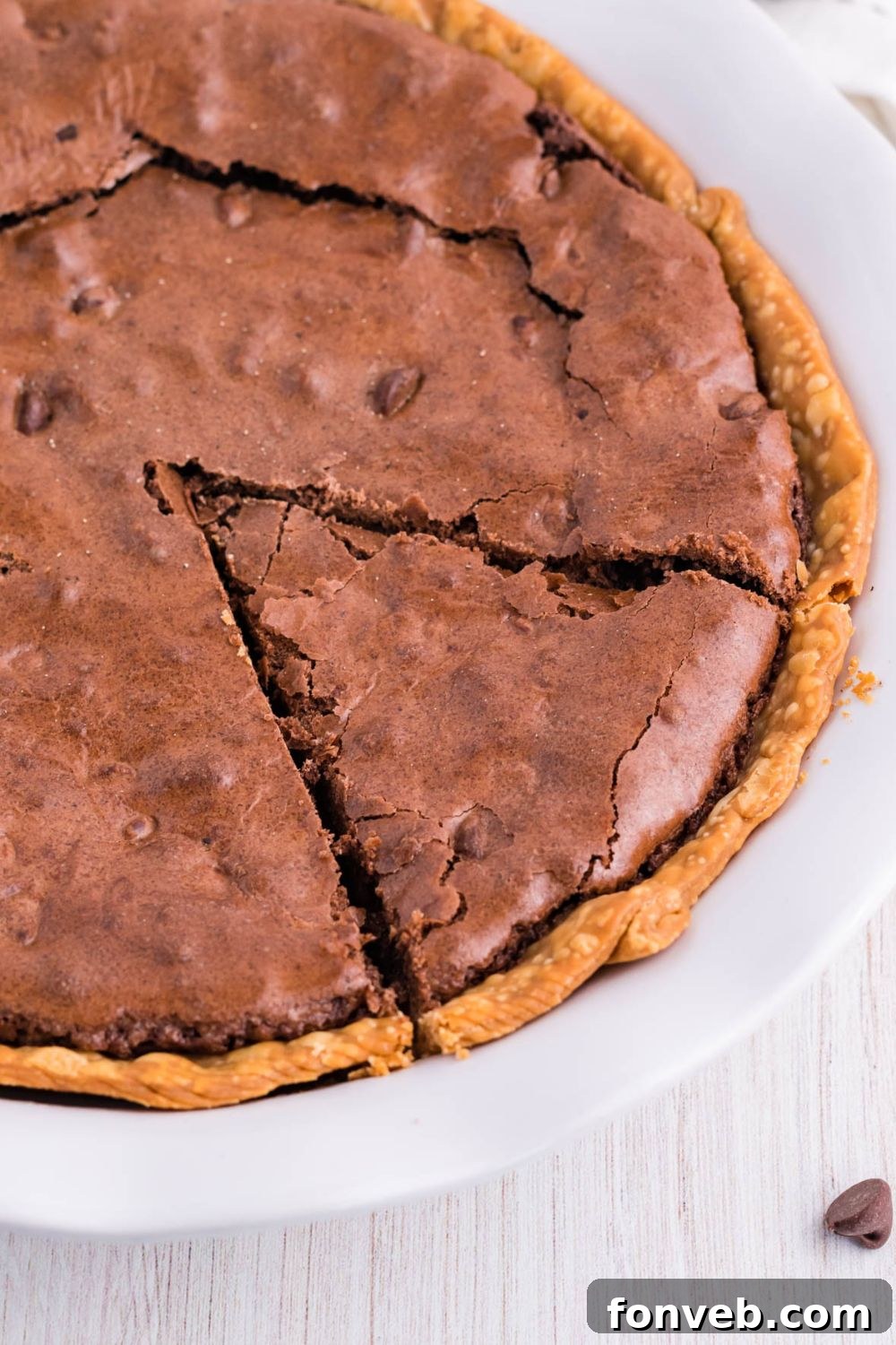 Fudgy Brownie Pie Perfection 4 A whole chocolate brownie pie with a slice carefully removed, revealing the gooey interior.