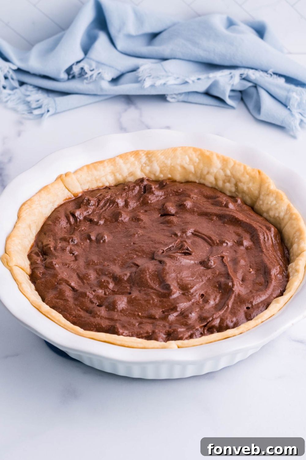 Fudgy Brownie Pie Perfection 10 Brownie batter neatly poured into a pie crust in a pan, ready for baking.