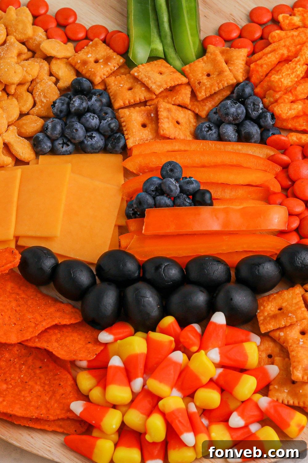 A fully formed jack-o-lantern shaped snack board, expertly arranged with diverse treats.