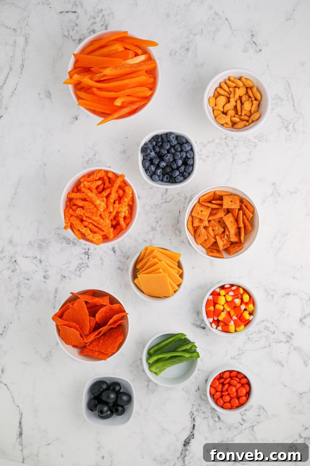 Close-up of Pumpkin Charcuterie Board ingredients neatly arranged in small bowls on a table, ready for assembly.