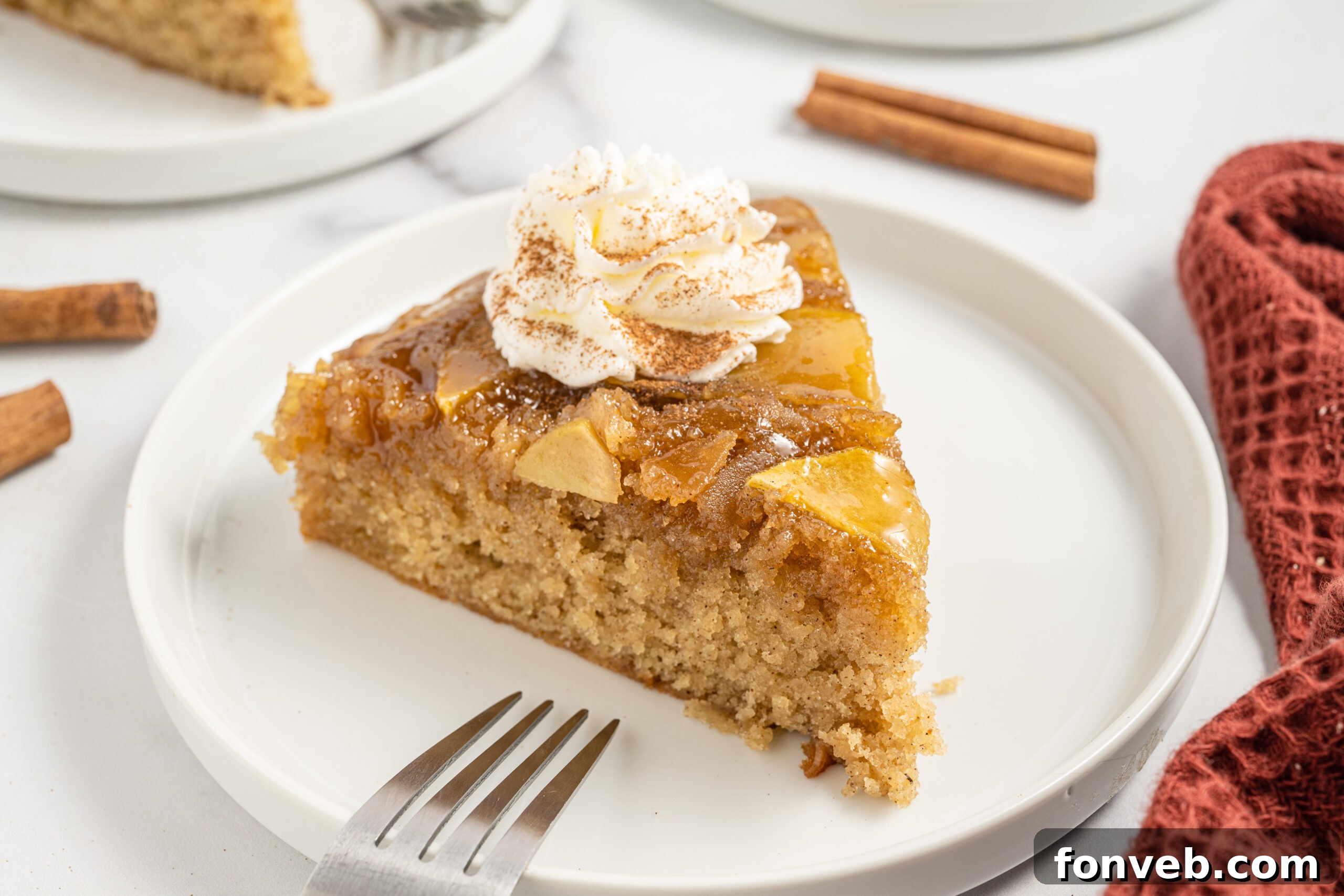 Caramelized Apple Bliss Cake 18 A beautifully presented slice of cake on a white plate, garnished with fluffy whipped cream