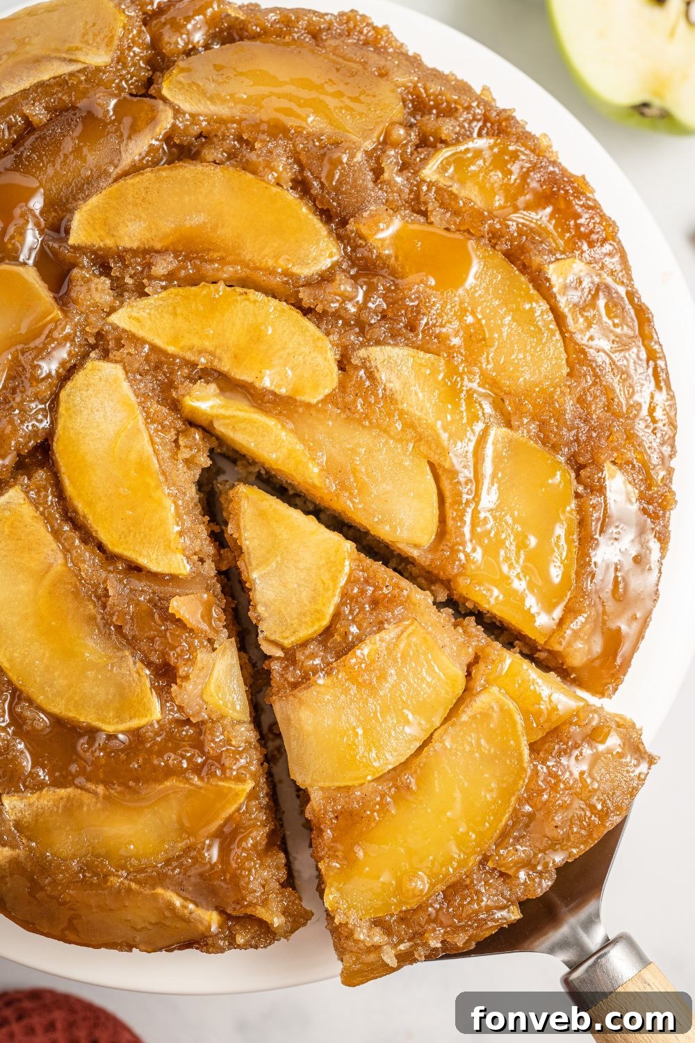 Caramelized Apple Bliss Cake 20 An overhead view of the apple upside down cake on a tray, with one slice being lifted from the whole cake