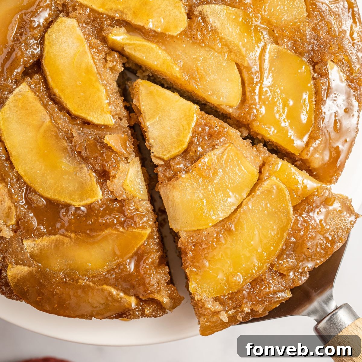 Caramelized Apple Bliss Cake 3 A slice of Apple Upside Down Cake being carefully lifted from the main cake, revealing its rich apple topping