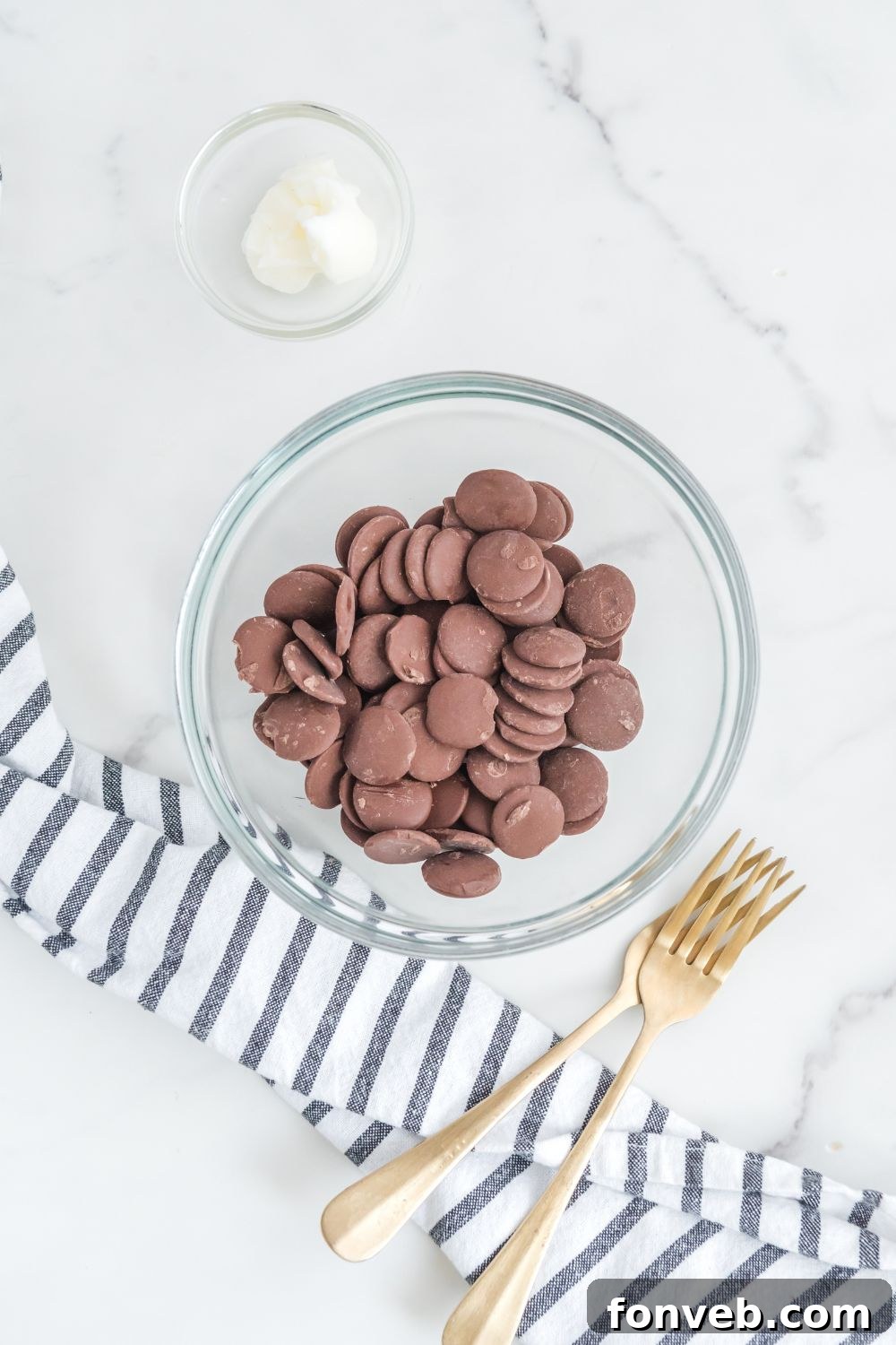 Bowl of dark chocolate melting wafers and Crisco on a kitchen counter, ready for melting
