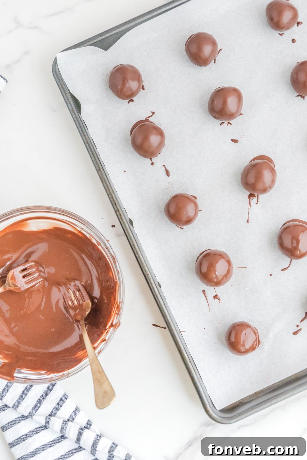 Rows of chocolate-dipped brownie bites cooling on a baking sheet lined with parchment paper