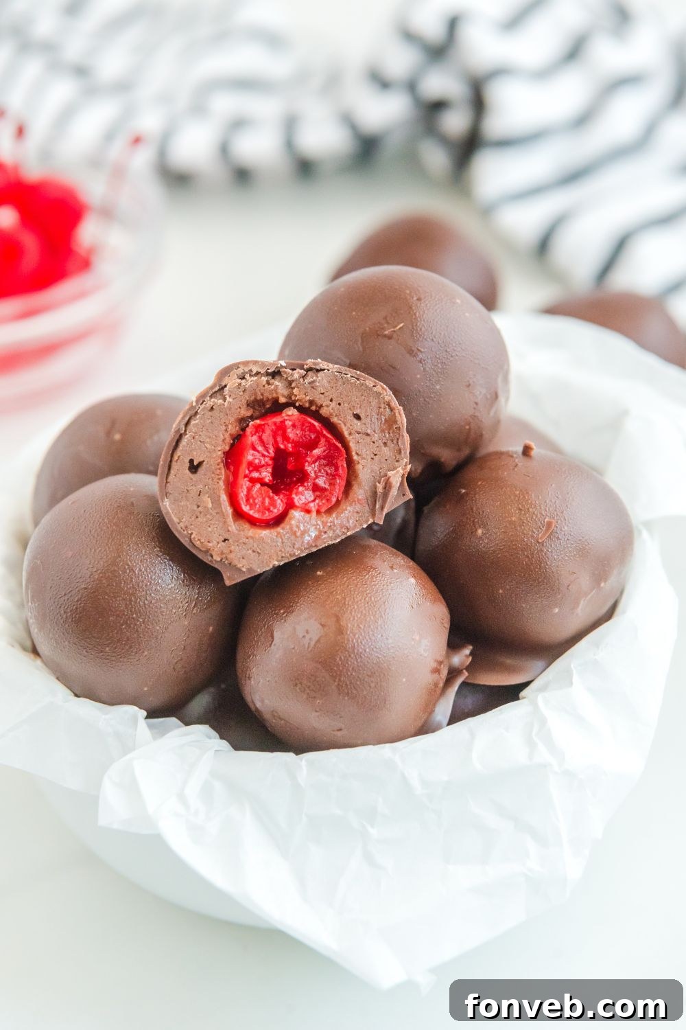 A bowl of Cherry Brownie Bombs with one cut in half, revealing the cherry center, on a clean table