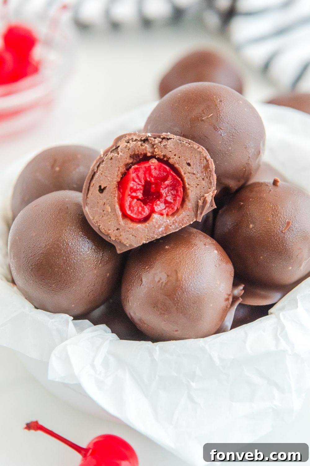 A bowl of Cherry Brownie Bombs surrounded by fresh cherries on a rustic table