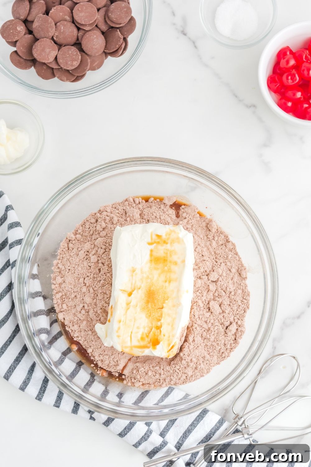 Brownie batter with cream cheese and vanilla in a mixing bowl, ready to be combined
