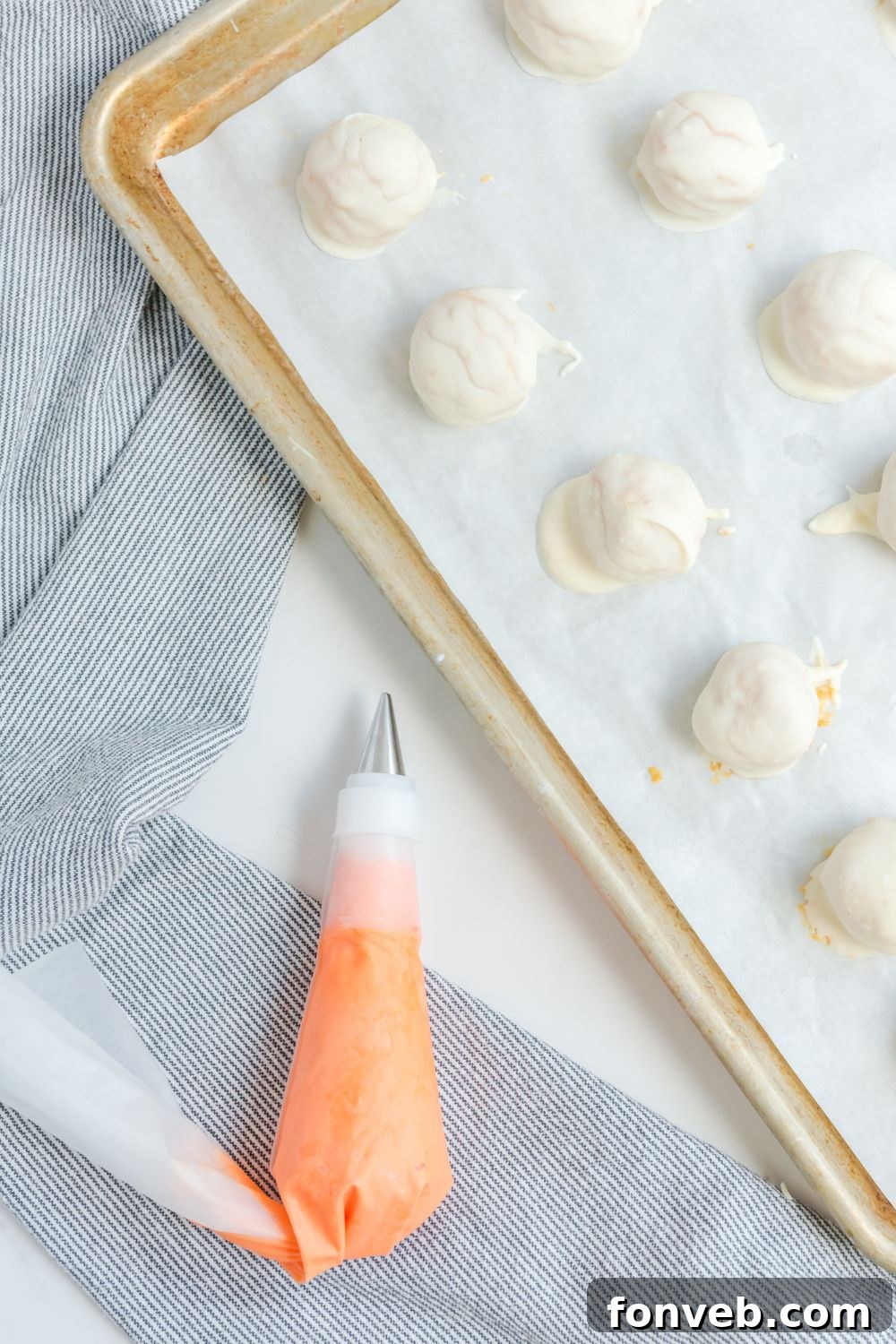 Several white chocolate-dipped pumpkin truffles arranged neatly on parchment paper.