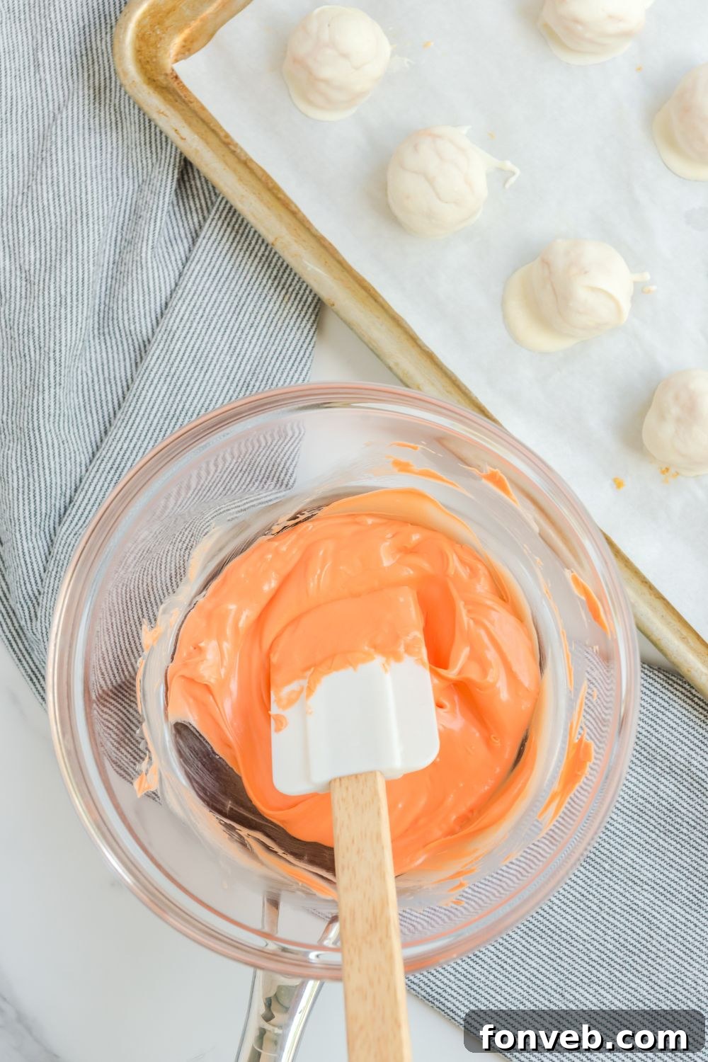 Vibrant orange candy melts, perfectly melted and ready for drizzling, in a bowl.