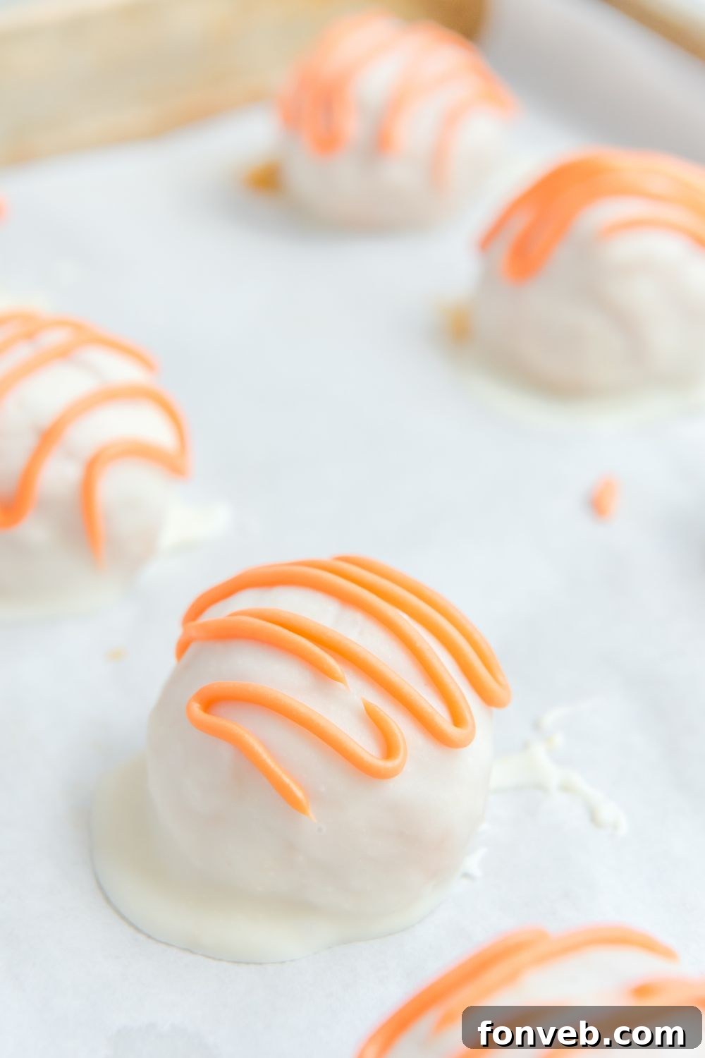 Finished White Chocolate Pumpkin Truffles, beautifully drizzled and set on parchment paper.