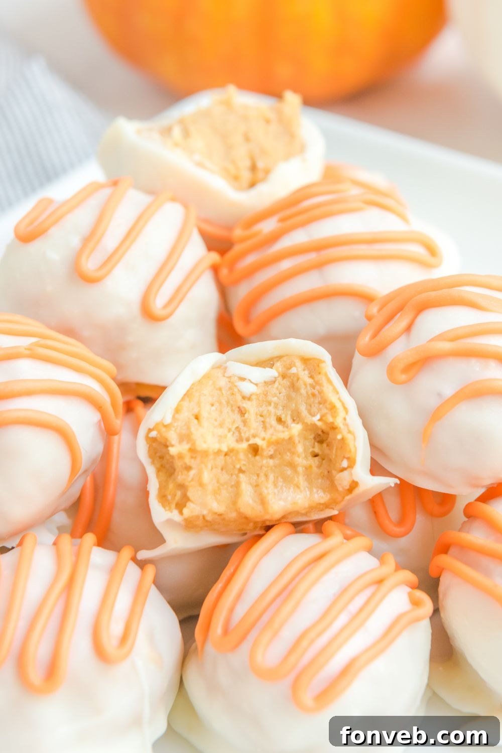 White Chocolate Pumpkin Truffles on a plate, with some having bites taken out, indicating their deliciousness.