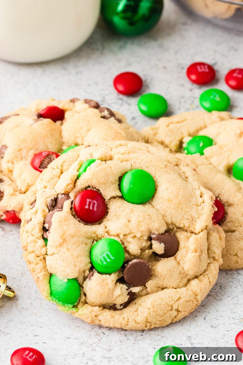 Festive M&M Delights 18 Christmas M&M cookies scattered on a table with loose M&Ms, highlighting their vibrant holiday colors and festive appeal