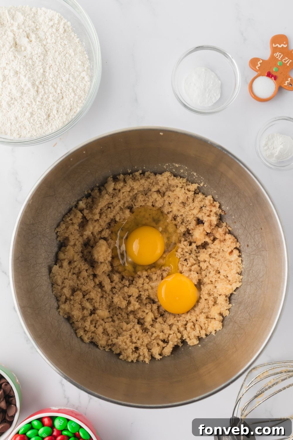 Festive M&M Delights 7 Eggs being mixed into a creamy butter and sugar mixture in a stand mixer bowl, showing the mixing process