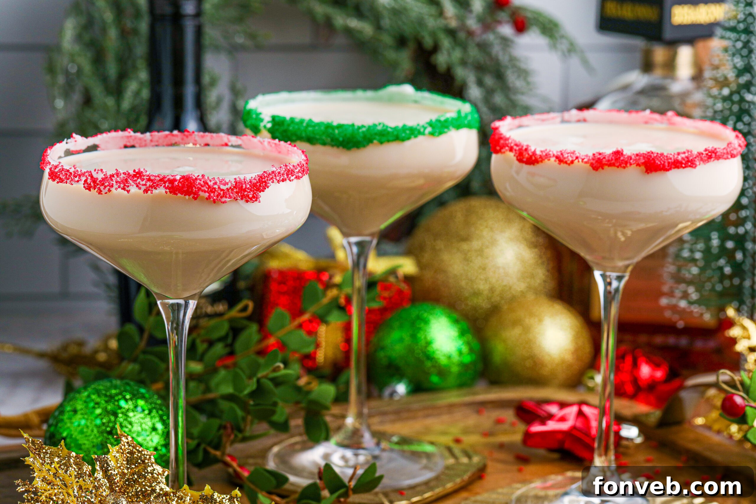 Festive Sugar Cookie Cocktails in glasses with vibrant red and green sugar rims on a rustic wooden table, ready for a holiday celebration.