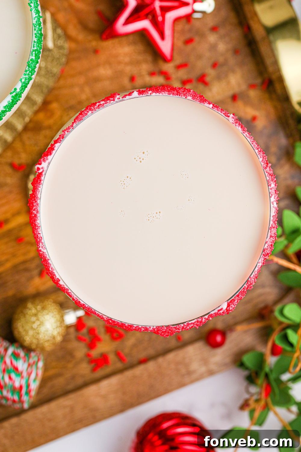 An inviting overhead shot of a Sugar Cookie Cocktail, garnished with a colorful sugar rim, placed on a wooden cutting board.