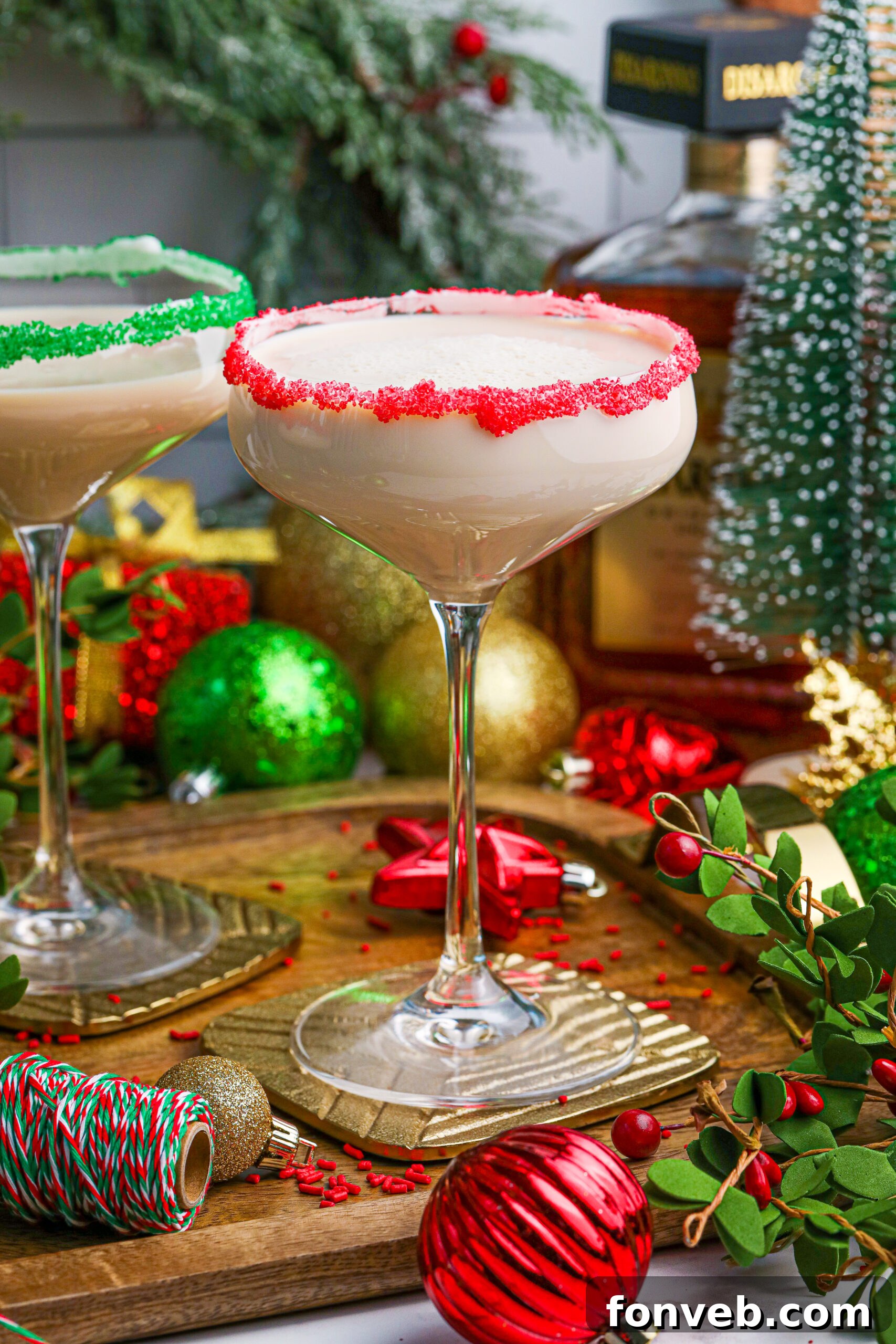 A single Sugar Cookie Cocktail in a glass with a striking red sugar rim, prominently displayed on a wooden table, emphasizing its elegant presentation.