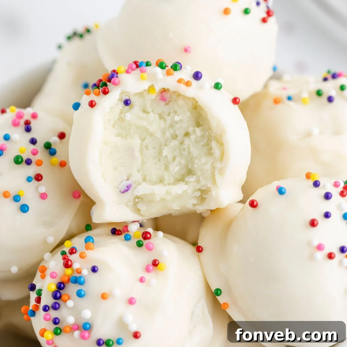 Lofthouse Sugar Cookie Truffles in a bowl with one that has a bite taken out of it