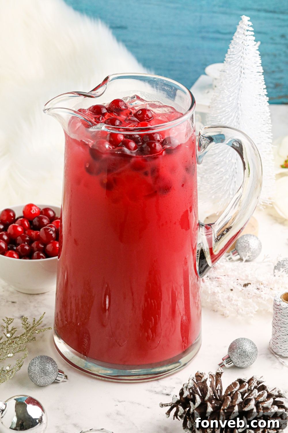 Mistletoe Magic Margarita 15 Cranberry rosemary margarita mixture displayed in a pitcher on a festive Christmas-decorated table.