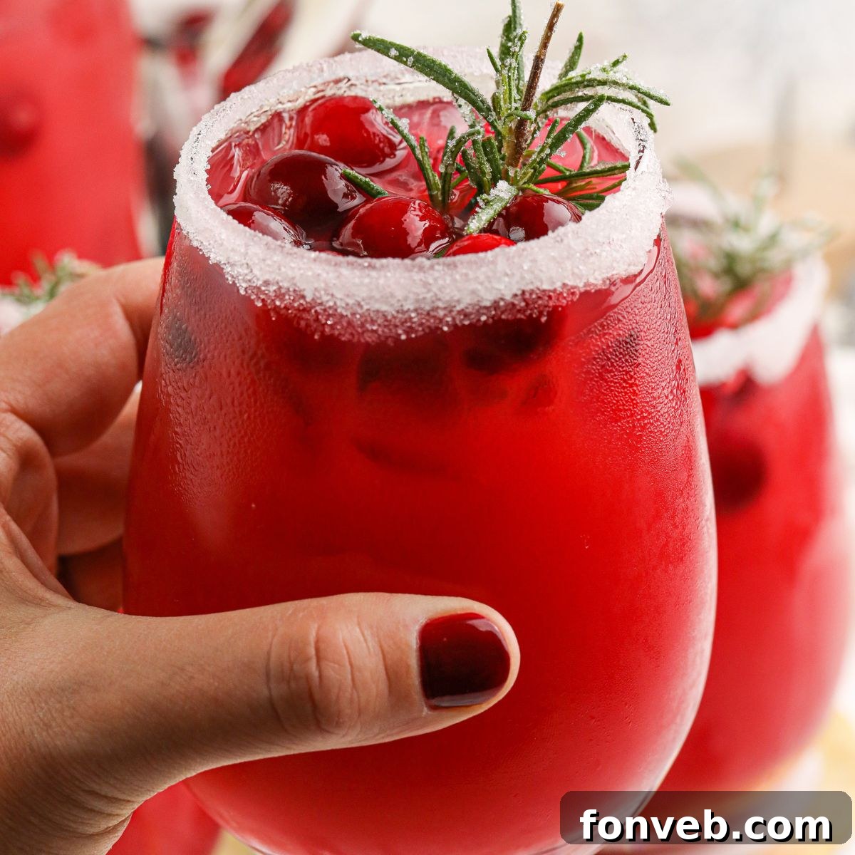 Mistletoe Magic Margarita 3 A hand holding a glass of Mistletoe Margarita, emphasizing the vibrant color and icy condensation.