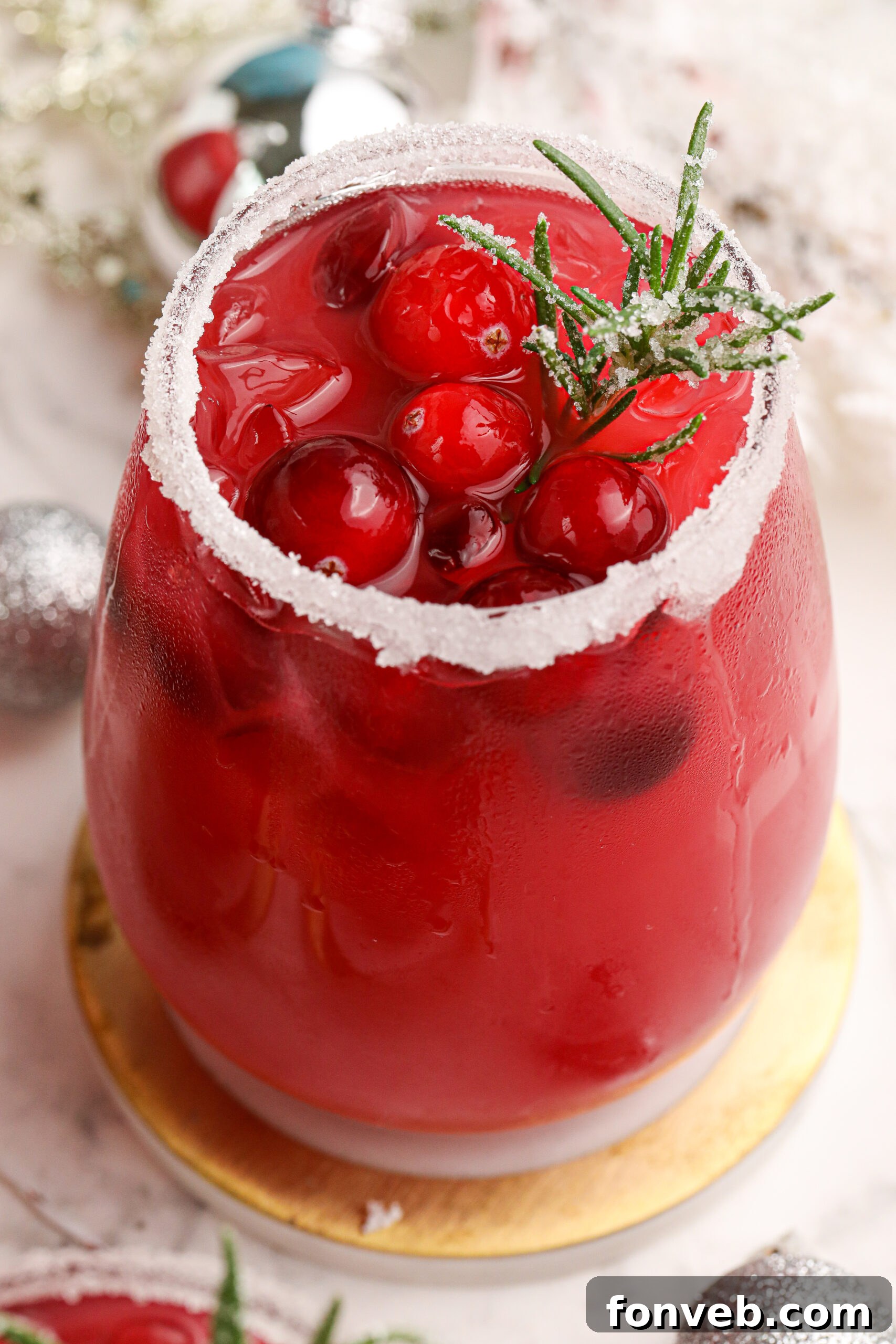Mistletoe Magic Margarita 6 A close-up of a Mistletoe Margarita glass, showing a sugar-rimmed edge and fresh cranberries inside.