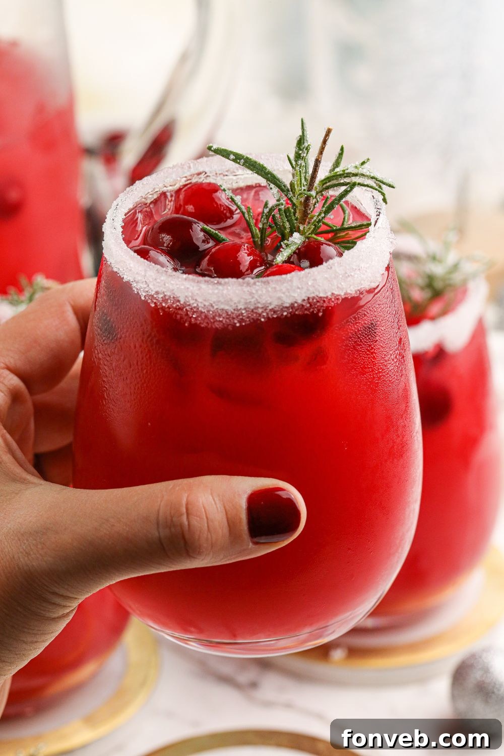 Mistletoe Magic Margarita 7 A hand holding a beautifully crafted cranberry cocktail, ready for enjoyment.