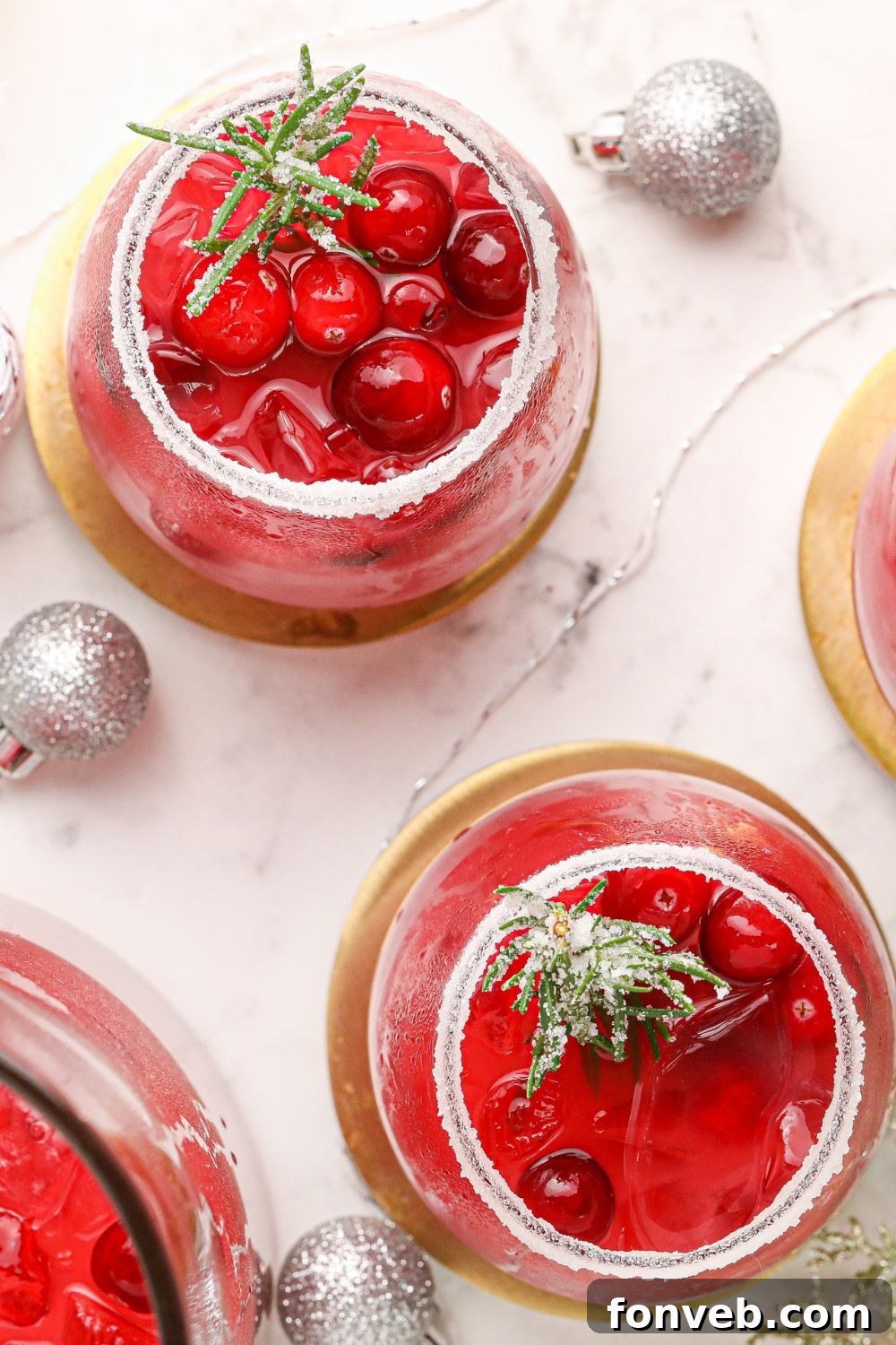 Mistletoe Magic Margarita 8 Glasses of cranberry margaritas surrounded by festive Christmas ornaments on a table.