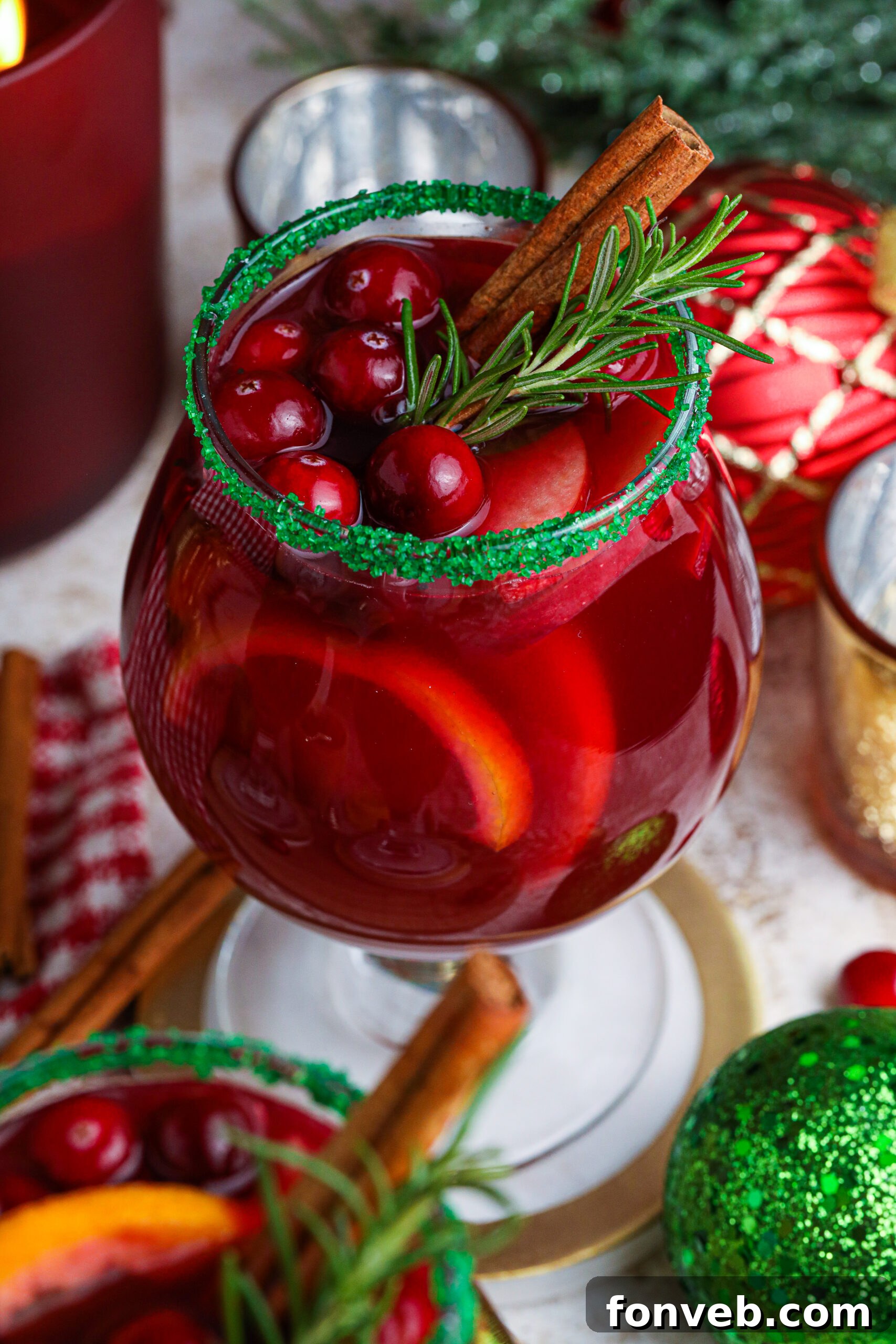 up close shot of red christmas sangria in clear glasses with a green sugar rim on a wood table