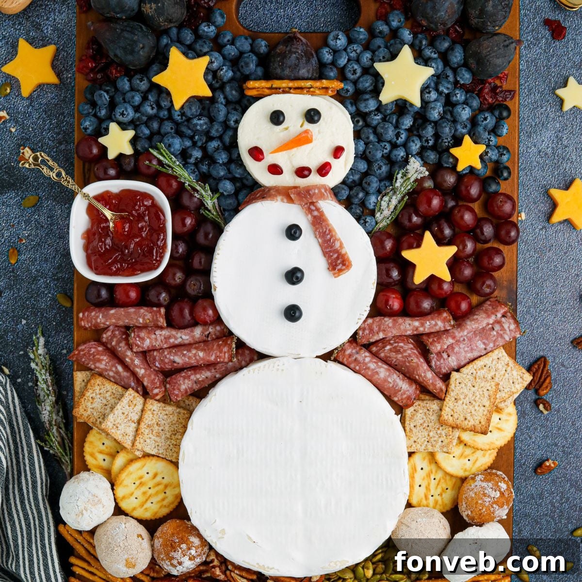 Snowman Charcuterie Board overhead look on table, showcasing an array of cheeses, meats, fruits, and crackers arranged around a snowman made of brie