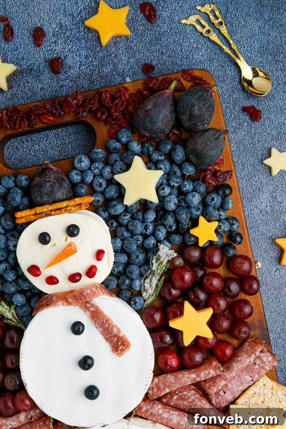 Side view of a complete snowman charcuterie platter on a table, highlighting the arrangement and variety