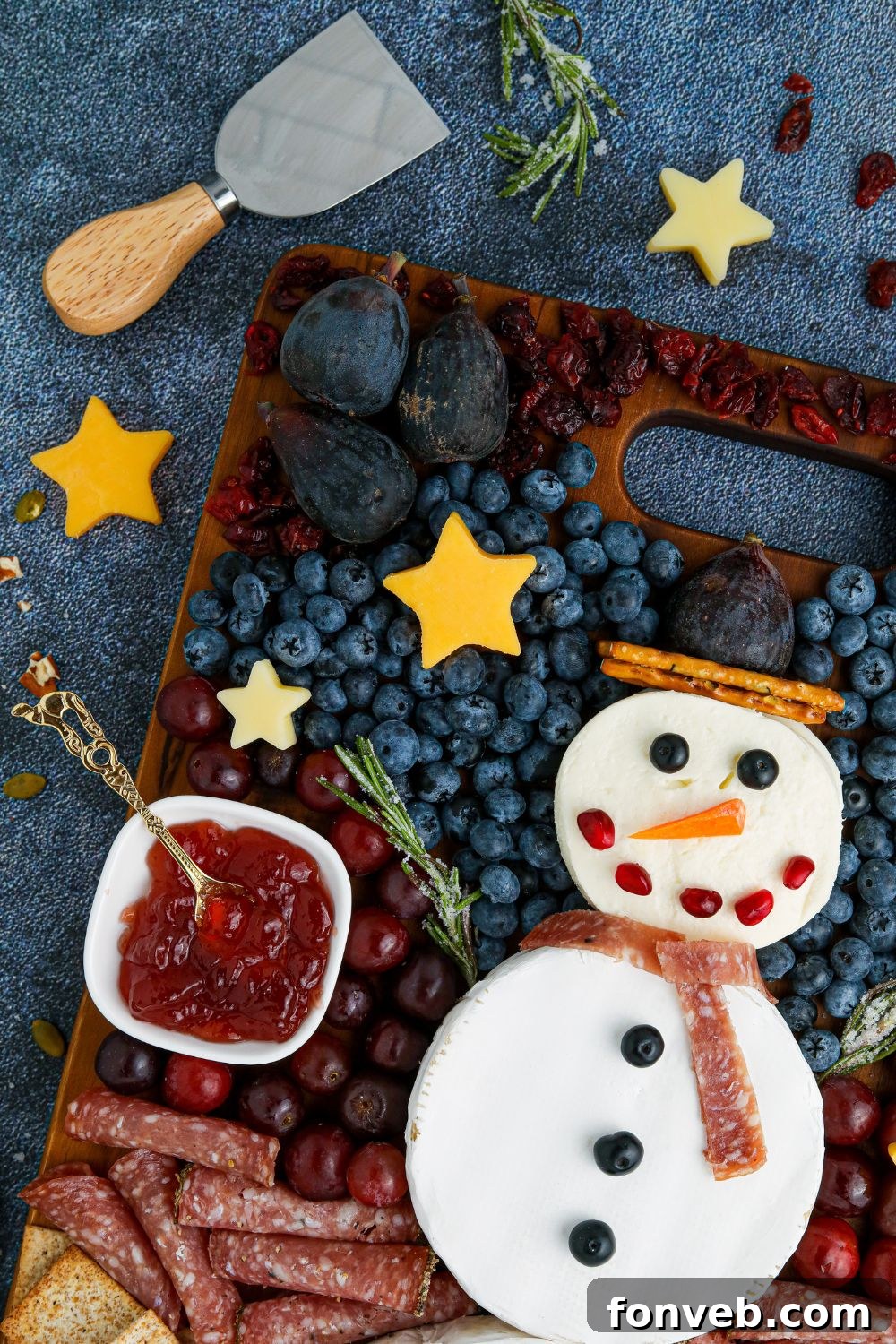 Festive snowman themed charcuterie tray on a rustic wooden table, ready for a holiday party