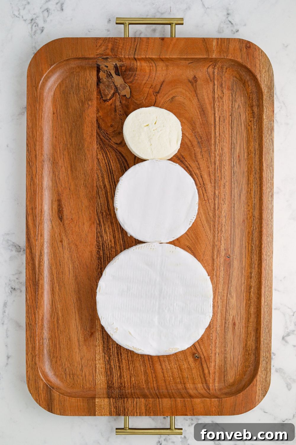 Close-up of cheese wheels on a serving platter, ready to be arranged into a snowman