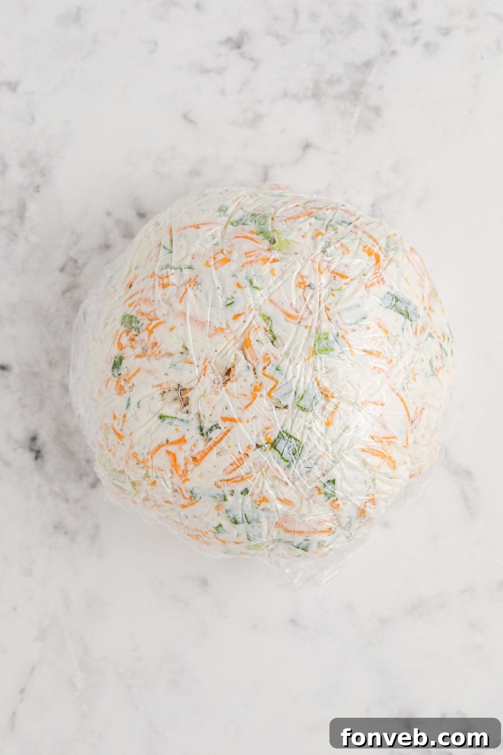 Rudolph's Holiday Charcuterie Platter 6 Cheeseball wrapped in plastic wrap chilling on a table