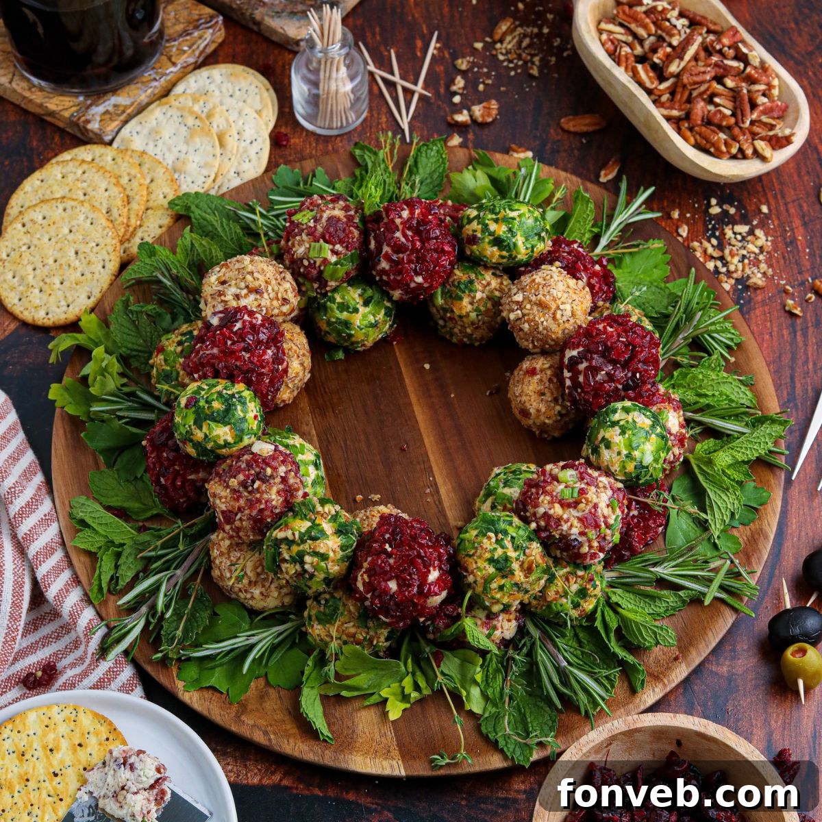 Overhead view of a vibrant dual-flavor cheese ball wreath platter adorned with fresh herbs on a table, ready for holiday serving.