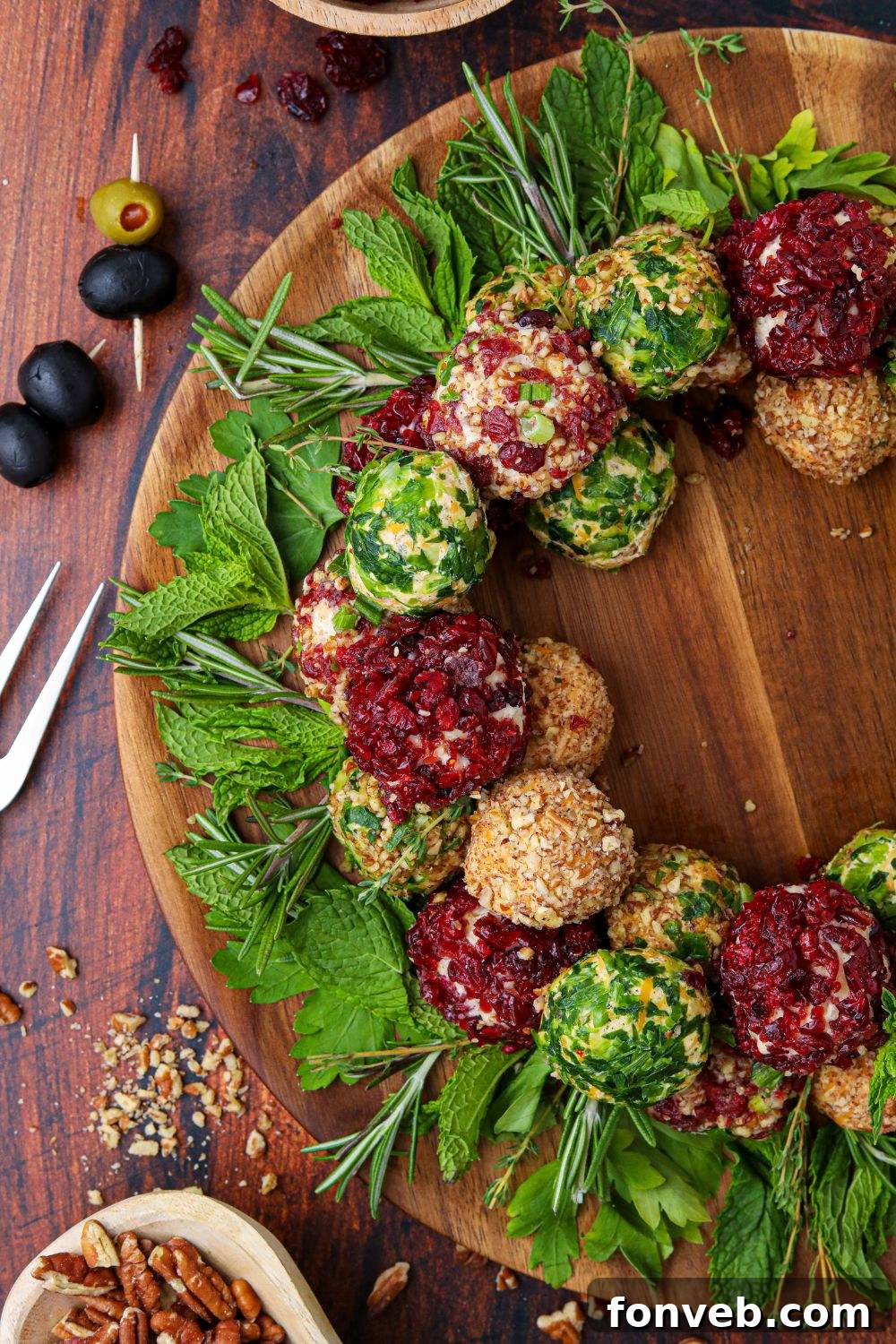 A segment of a cheese ball wreath displayed on a wooden table, surrounded by an array of various food items.
