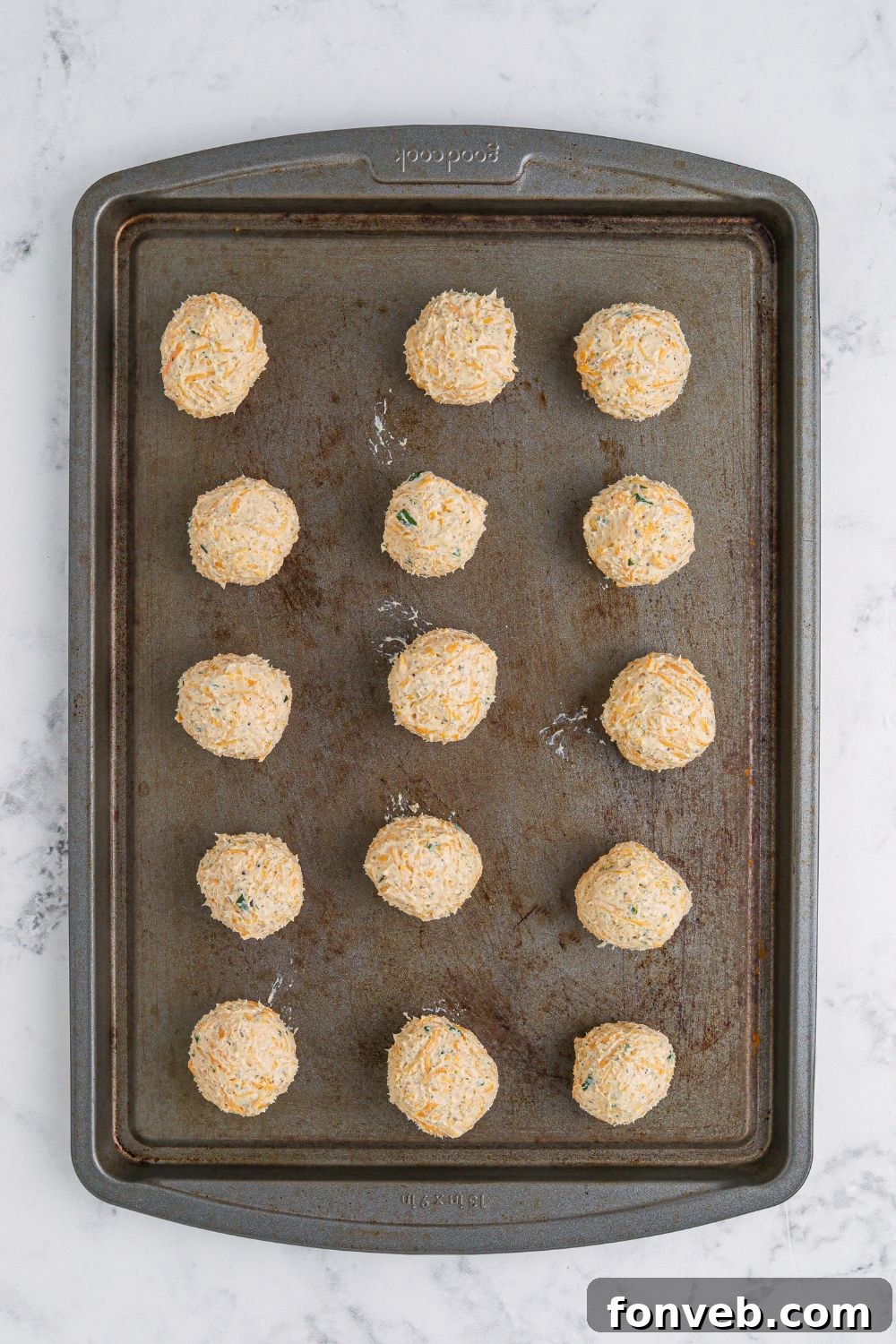 Perfectly shaped mini cheese balls, plain and ready for their flavorful coatings, arranged on a surface.