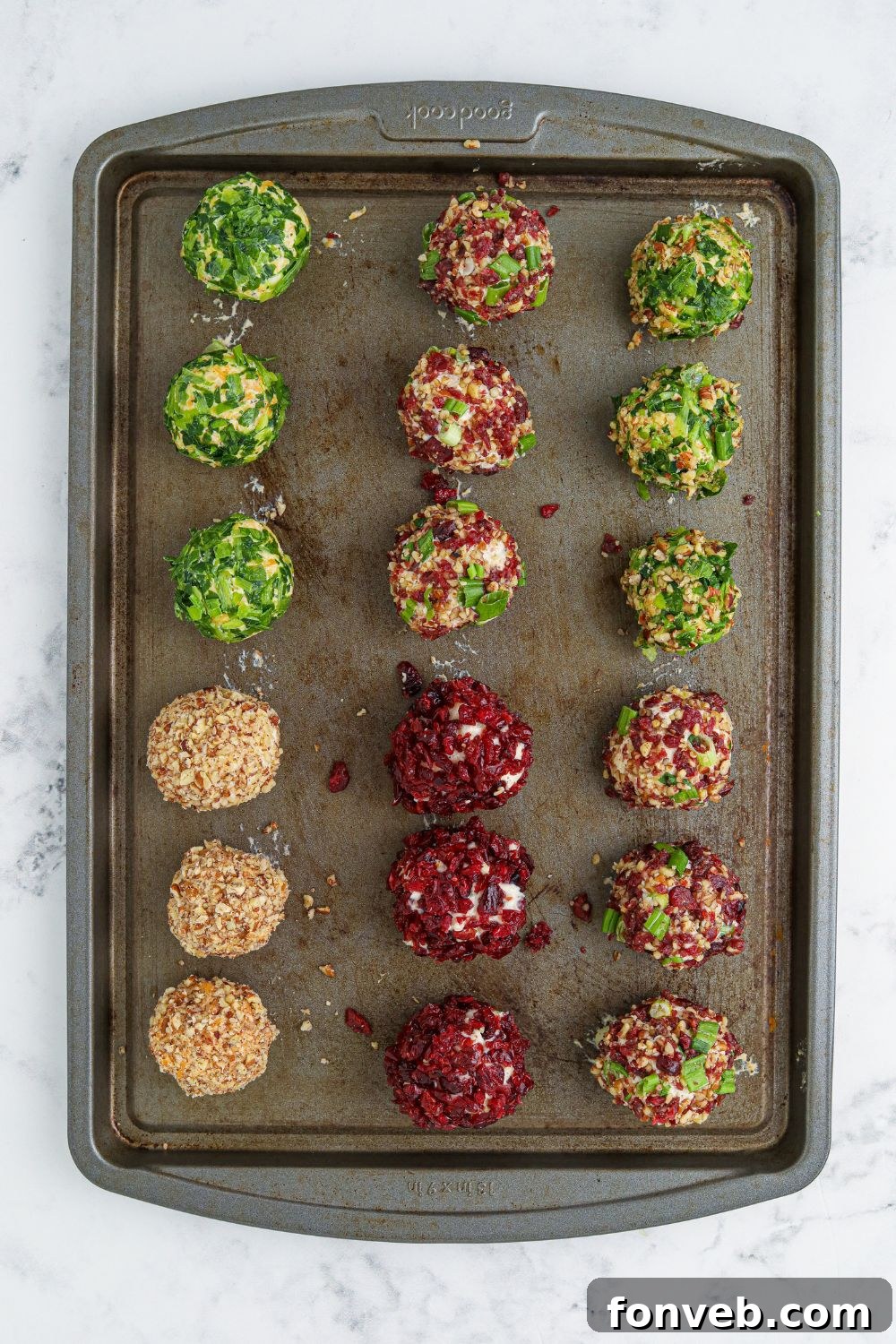 Mini cheese balls organized on a cookie sheet, prepared for chilling.