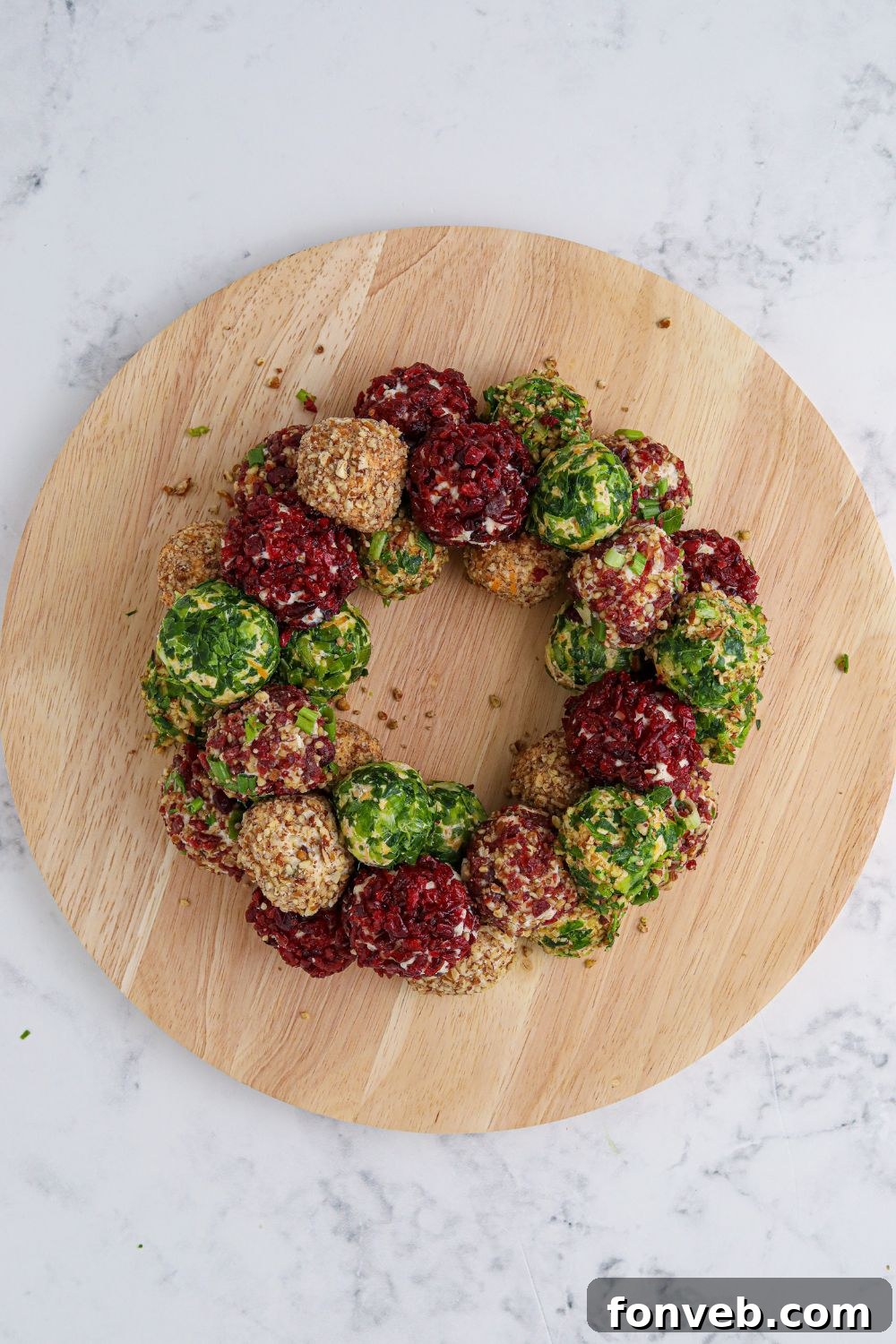 A circular board with the initial ring of cheese balls forming the base of the wreath.