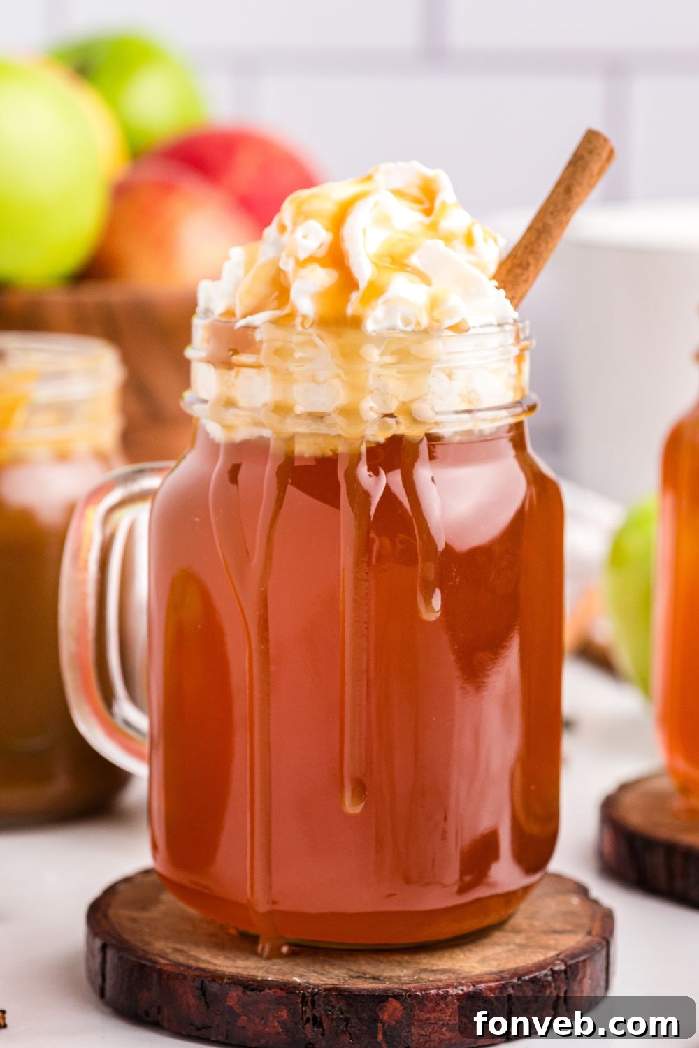 Cozy Caramel Apple Brew 11 A mason jar mug filled with caramel apple cider, topped with a generous swirl of whipped cream and a drizzle of caramel.