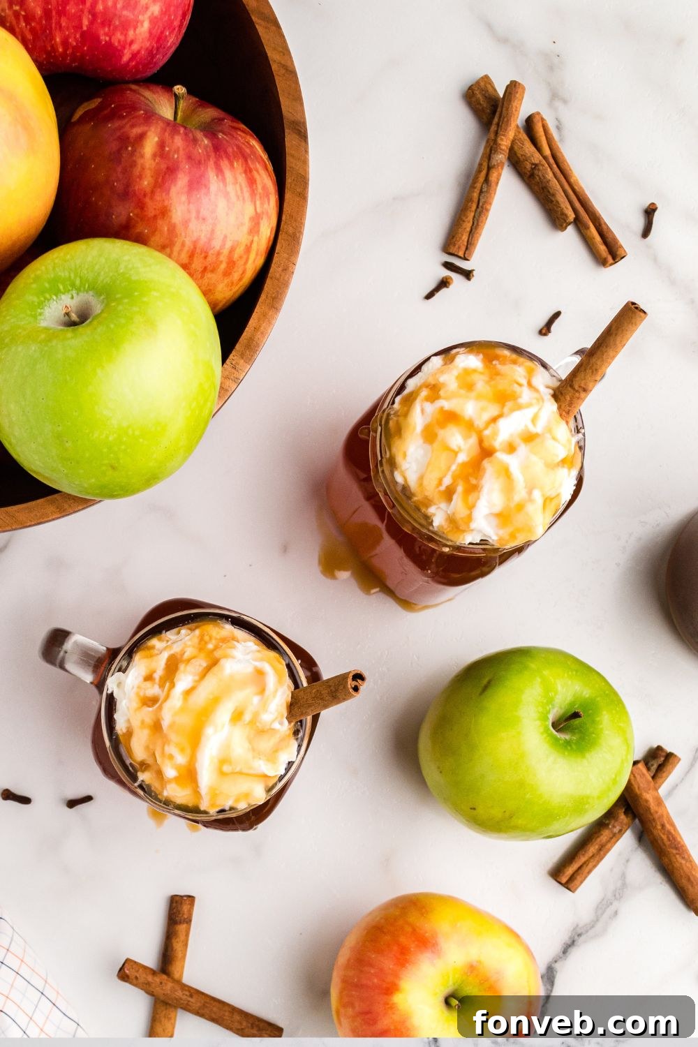 Cozy Caramel Apple Brew 12 Glasses of cider arranged on a wooden table, surrounded by fresh apples and cinnamon sticks, creating a festive autumn scene.