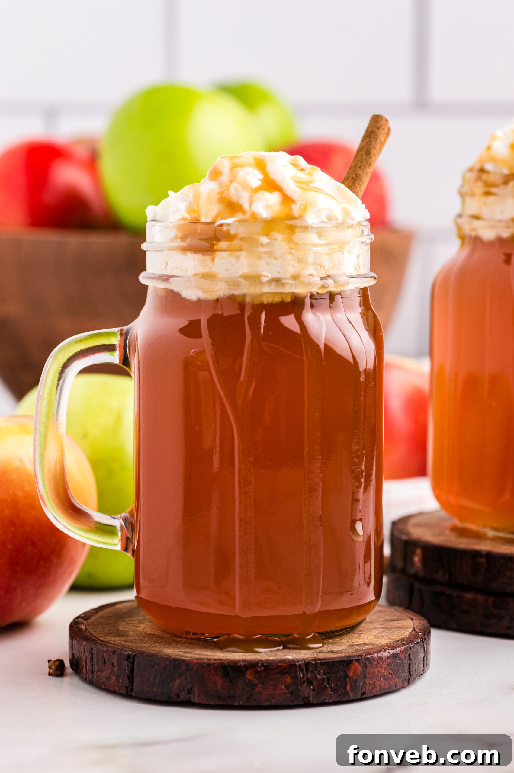 Cozy Caramel Apple Brew 15 A mason jar filled with Crock Pot Caramel Apple Cider, topped with whipped cream and a luxurious caramel syrup drizzle, ready to be savored.